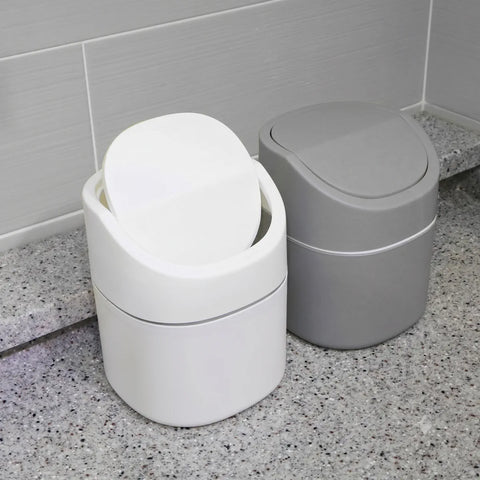 Two trash bins, one white and one gray, on a speckled countertop.