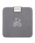 Gray textured bath mat with a teddy bear design and a visible brand label on a white background.
