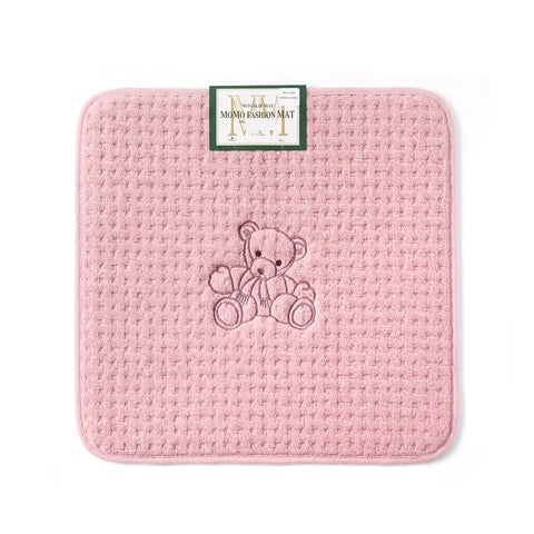 Pink textured mat with an embroidered teddy bear design on a white background