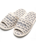 Pair of checkered slippers with 'Cotton House' branding on a white background