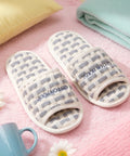 Pair of striped slippers on a pink surface with a mug and flowers.
