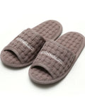 Pair of gray slippers with 'Cotton House' branding on a white background