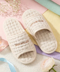 Ivory slippers with 'Cotton House' branding on a soft pastel background.