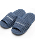Pair of blue textured slippers with 'Cotton House' branding on a white background
