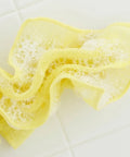 Yellow sponge cloth with foam on a white tiled background