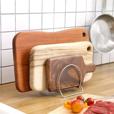 3 different types of wooden cutting boards standing upright in a stainless steel organizer.