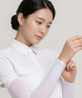 Woman wearing a white shirt with sheer sleeves against a plain background