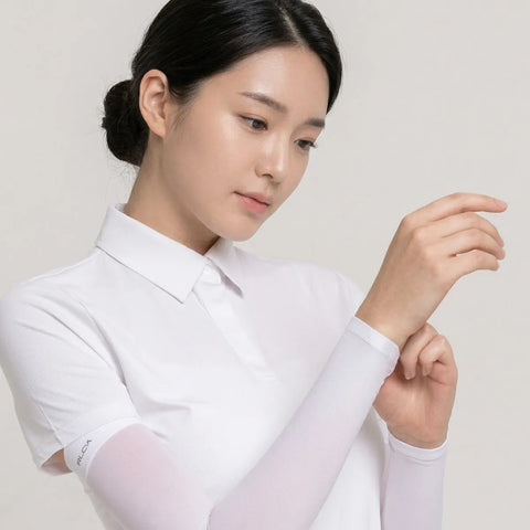 Woman wearing a white shirt with sheer sleeves against a plain background
