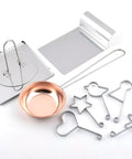 Set of metal cookie cutters and a copper-colored measuring cup on a white background