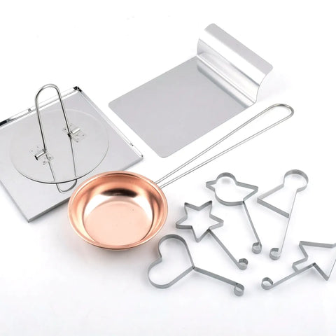 Set of metal cookie cutters and a copper-colored measuring cup on a white background
