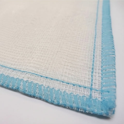 A close-up of a white woven fabric with a light blue stitched border, showing the texture of the material.