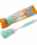 A mint green and white sponge cleaning brush with a white handle is shown in front of its orange and blue retail packaging on a white background.