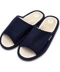 A pair of dark navy blue open-toe slippers with textured beige footbeds featuring a circular design and raised nodule details, shown on a plain white background.