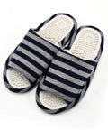 A pair of open-toe slide sandals with navy blue and gray horizontal stripes, featuring textured white footbeds with raised nodule details, shown on a plain white background.