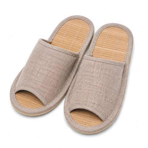 A pair of open-toe slip-on slippers with a beige woven fabric upper and a light tan bamboo-look footbed, shown on a plain white background.