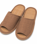 A pair of open-toe slip-on slippers with a brown woven fabric upper and a light tan bamboo-look footbed, shown on a plain white background.