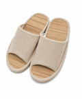 A pair of open-toe slip-on slippers with beige woven fabric uppers and natural bamboo-look footbeds, shown on a plain white background.