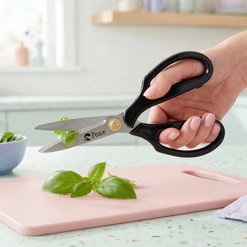 Hand holding a pair of scissors with 'Peace' branding over a pink cutting board with basil leaves.