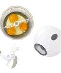 Small blender with eggs inside and a white handheld blender on a white background