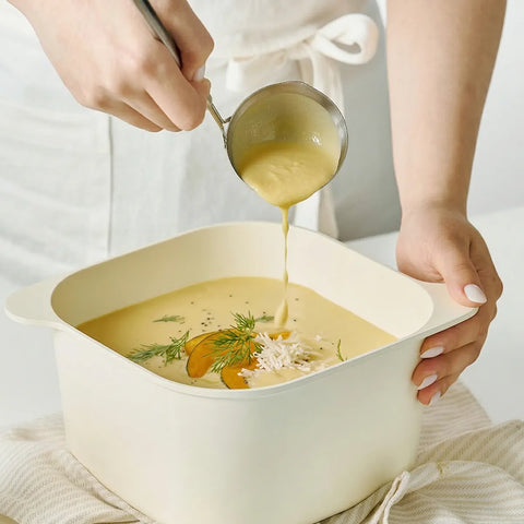 Person ladling soup into a bowl with a white background