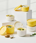 Set of yellow and white food containers with lids on a light background
