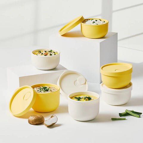 Set of yellow and white food containers with lids on a light background