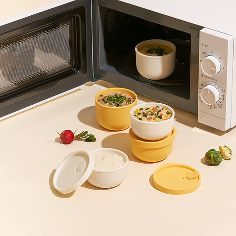 Assorted rice containers stacked on top of each other with an open microwave in the background