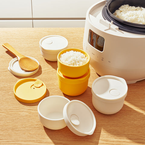 Set of yellow and white rice containers with a rice cooker in the background.