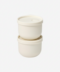Two white silicone containers with lids on a white background