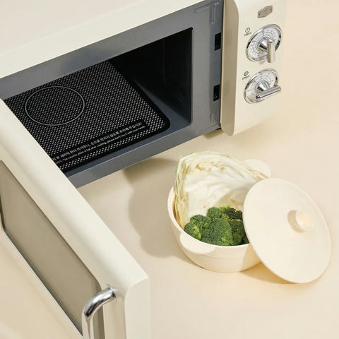 Vintage-style microwave oven with a bowl of vegetables on a kitchen counter.