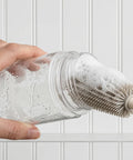 Cleaning brush with bubbles and soap cleaning an open clear jar