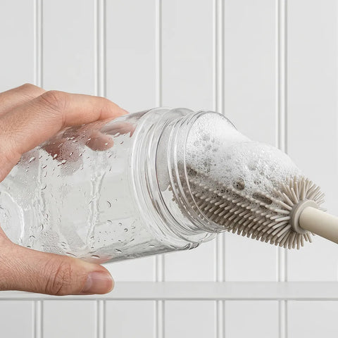 Cleaning brush with bubbles and soap cleaning an open clear jar
