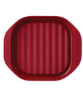 Red silicone baking mat with textured surface on a white background