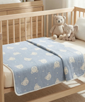 Wooden crib with a blue baby blanket featuring animal patterns and two plush toys inside.