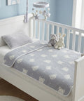 Crib with a gray crib sheet featuring bear patterns, stuffed animals, and a star mobile in a nursery.