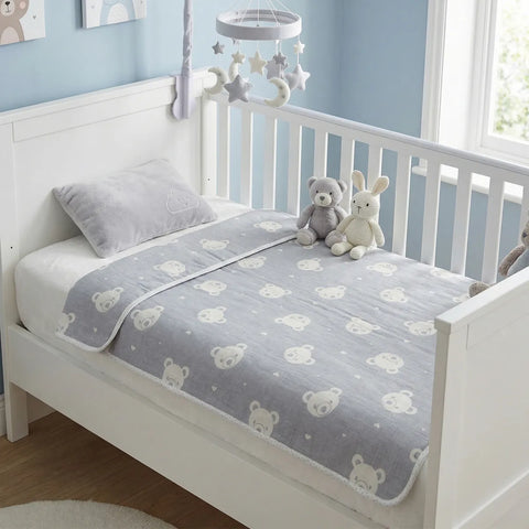 Crib with a gray crib sheet featuring bear patterns, stuffed animals, and a star mobile in a nursery.