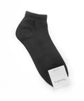 Black ankle sock with a white label on a white background