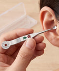 Person using a silver ear cleaning tool to clean their ear with a beige background
