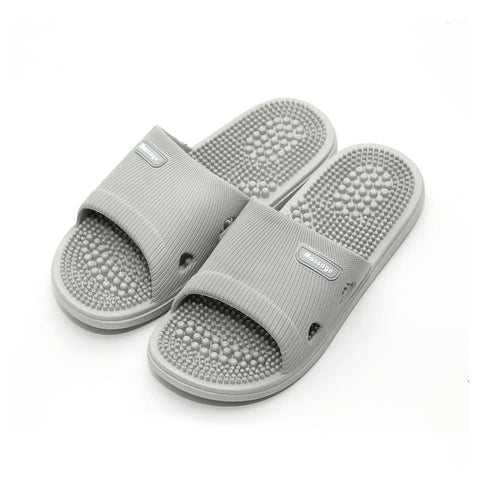 Pair of gray slippers with acupressure balls on a white background