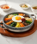 Stone pot bibimbap with various ingredients on a wooden tray
