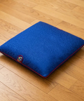 Blue pillow with a colorful emblem on a wooden floor