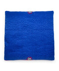 Blue textured square seat cushion with an embroidered design on a white background