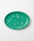 An oval green melamine plate with a white speckled pattern, photographed from directly above on a clean white background.