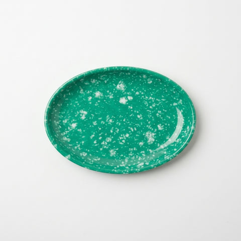 An oval green melamine plate with a white speckled pattern, photographed from directly above on a clean white background.