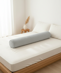 Gray cylindrical pillow on a bed in a bright bedroom