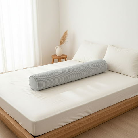 Gray cylindrical pillow on a bed in a bright bedroom