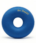 Blue donut-shaped pillow with 'Be Happy' text on a white background