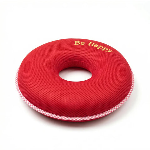 Red donut-shaped pillow with 'Be Happy' text on a white background
