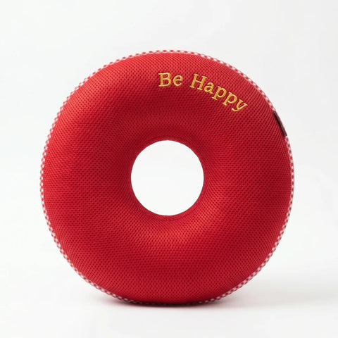 Red donut-shaped pillow with 'Be Happy' text on a white background