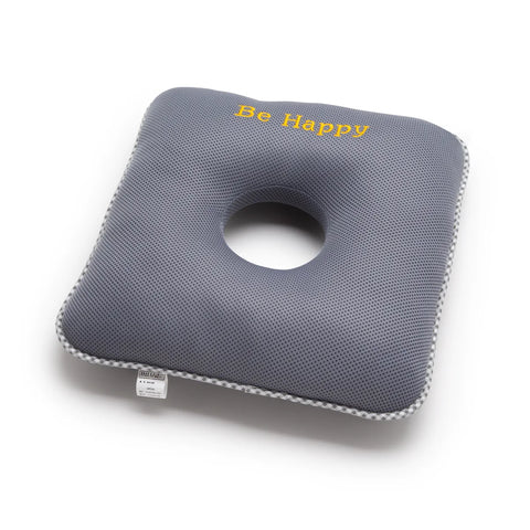 Gray square donut pillow with a circular hole and 'Be Happy' text on a white background